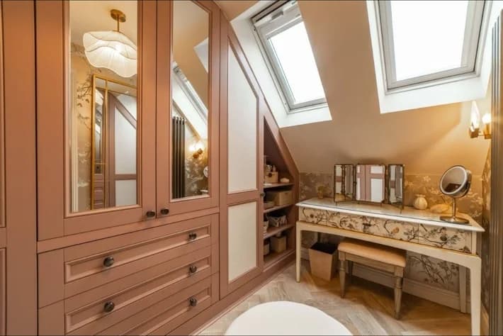 Fitted wardrobes and a dressing area built into loft eaves beneath skylights