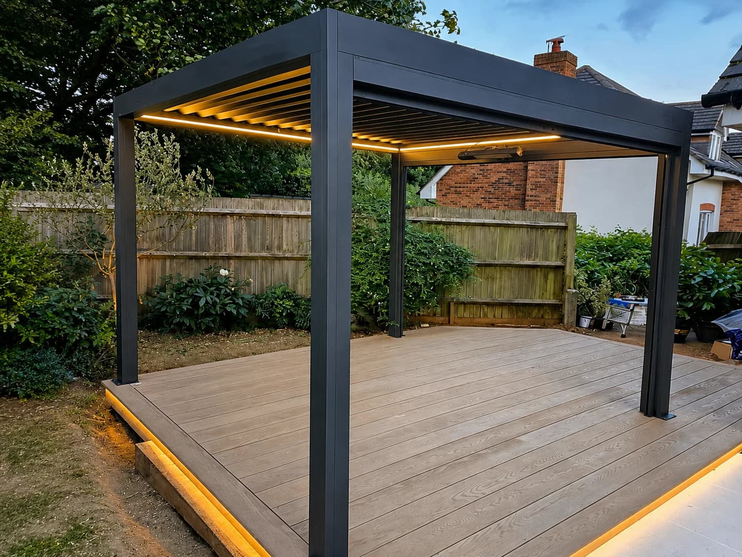 Modern dark pergola with integrated lighting over a composite deck at dusk